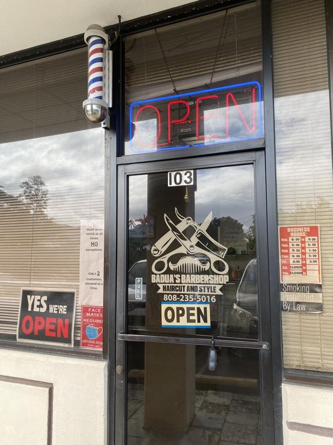 Barber pole and OPEN sign at the door of Badua's Barbershop